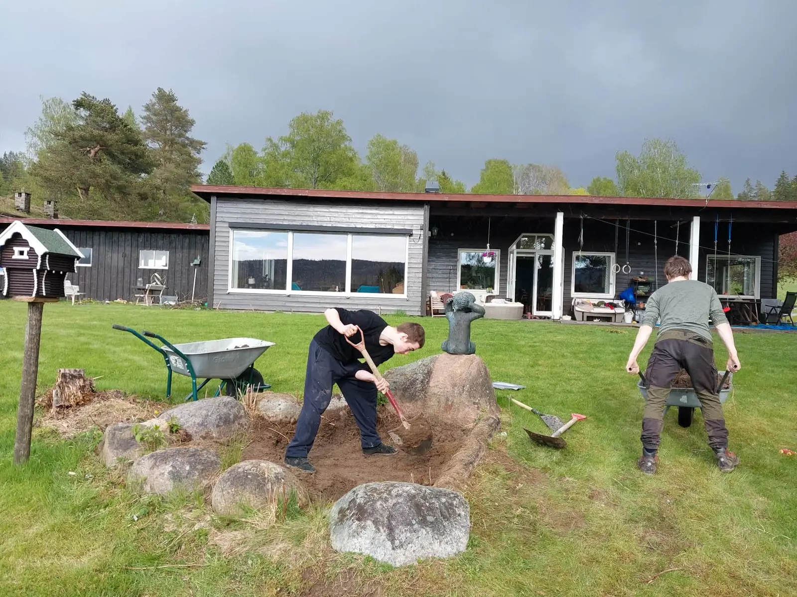 To ungdommer graver et hagebed med spader foran et hus.